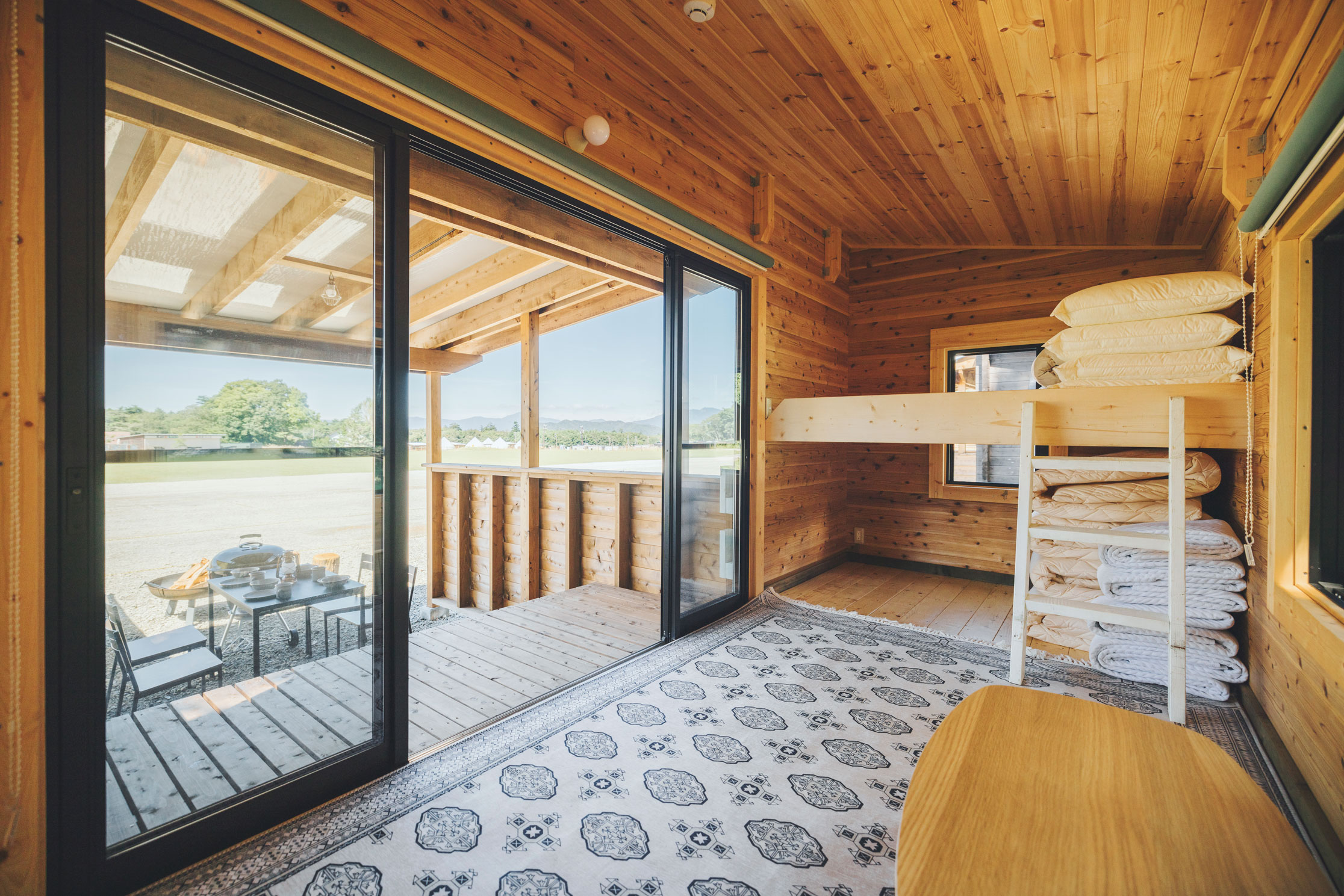グランピング客室として活用できるログ小屋の内観。二段ベッドと大開口の窓